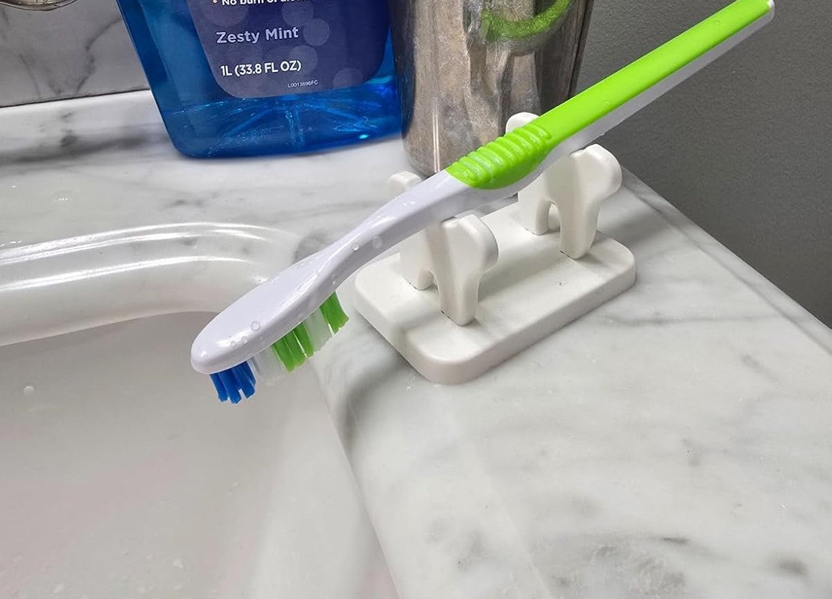 Toothbrush with blue bristles on a white sink next to a bottle of mouthwash.